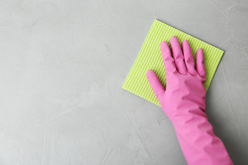 Woman in gloves wiping grey table with rag, top view. Space for text