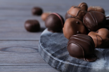 Tasty chocolate candies on grey marble board closeup. Space for text