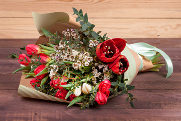 bouquet of flowers with tulips, chamelaucium and eucalyptus on a wooden table. high quality