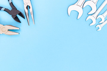 Tools worker, different pliers and many wrenchs on a blue background, top view with free space