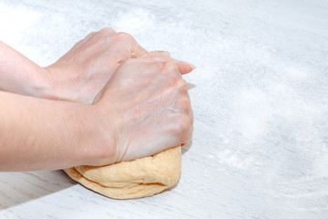 Close-up hands woman kneading dough in the kitchen at home