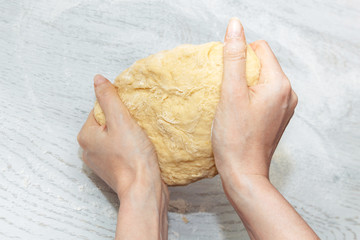 girl is holding a raw dough for buns. the concept of home cooking. making homemade dough