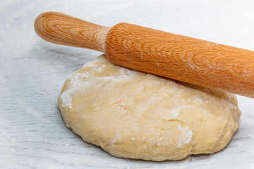 dough and rolling pin on the white kitchen table. the concept of home cooking. cooking homemade dough. close up