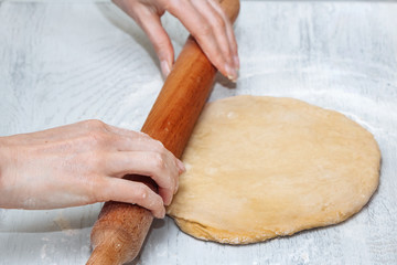 girl rolls out raw dough in the kitchen. the concept of home cooking. making homemade dough