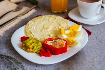 Arepa paisa with eggs, ham and cream cheese. Guacamole as an accompaniment (Colombian breakfast)