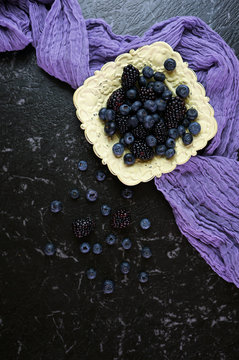 Summer berries with blueberries and blackberries in vintage dish creative flatlay top view Dark moody creative composition vertical orientation.