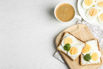 Tasty egg sandwiches served with coffee on white wooden table, flat lay. Space for text