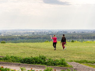 girl in red and girl in black go away from the viewer to the far horizon, selective focus