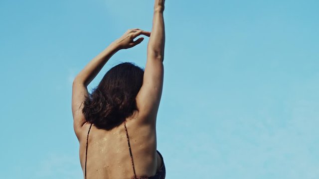 Beautiful brunette caucasian woman wearing a dress posing sensually moving, back shot. Slow motion.