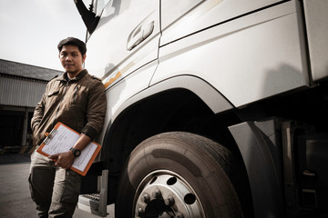 portrait of Asian a truck driver holding clipboard inspecting safety a truck, vehicle maintenance checklist a truck, road freight industry logistics.