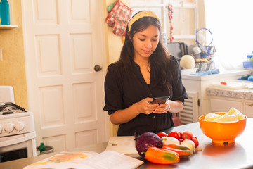 Woman taking photo of food while cooking - young woman preparing delicious salad at home while...