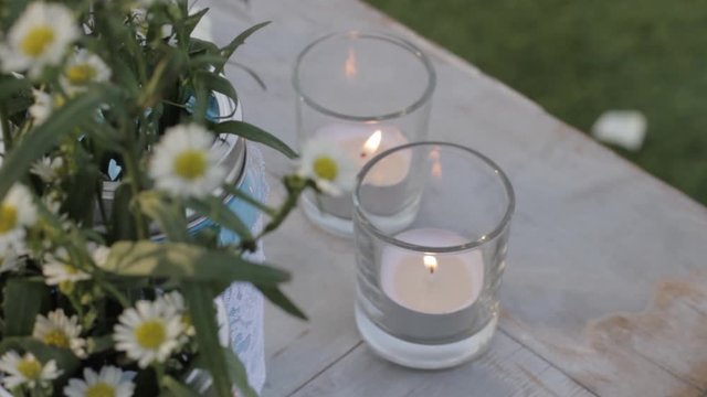 Wedding Table Decorations with Daisy Flowers and Lit Candles at Sunset