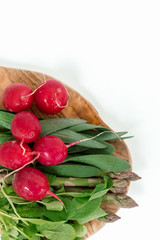 Set of vegetables on a wooden cutting board on a white background: radish, lettuce, asparagus, green onions. New crop of fresh greens. Healthy food. Copy space.Top view point.