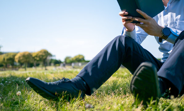 草原で本を読むビジネスマン