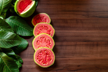 Closeup on red guava sliced with green leaf on rustic wooden background