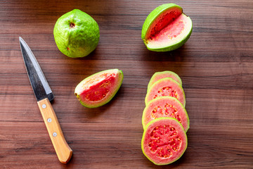 Antique steel knife and sliced red guavas on rustic wooden background