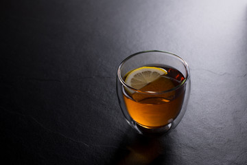 Cup of tea with lemon on black granite background