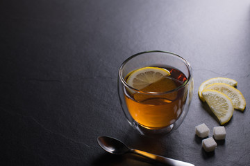 Cup of tea with lemon on black granite background