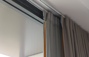 Curtain rail with gray curtain, tulle and wooden Handle. Curtain decoration and interior design in...