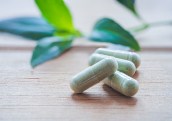 Herb capsule isolated on wooden.