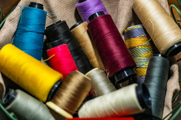 Various colors of thread rolls sits in wooden basket 
