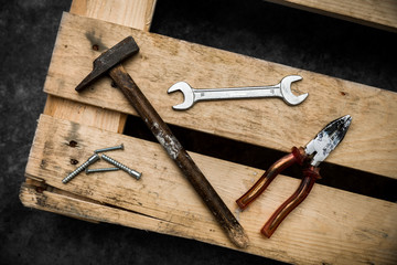 heavily used metal and wood hammer on top of a wooden pallet and screws 