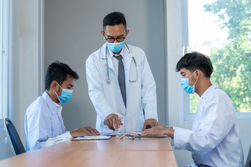 Doctor wearing protective mask to Protect Against Covid-19 meeting at hospital,Digital tablet laptop computer smart phone using,Medical technology network team meeting concept.