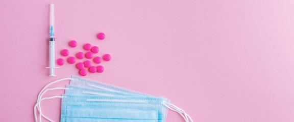 Medical mask surgical protective virus, flu, disease, pills and syringe. Isolated on a pink background.