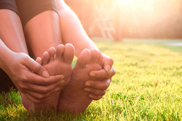 Foot pain .Woman sitting on grass Her hand caught at the foot. Having painful feet and stretching...