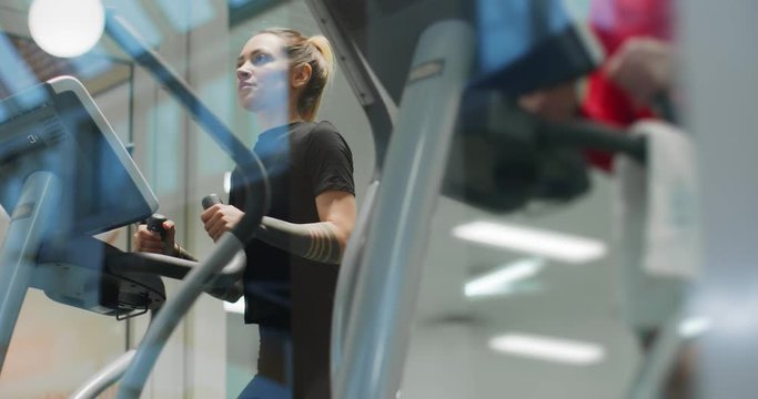 woman exercising with elliptical walking machine at gym.Front view, slow motion. Woman training at walking machine. Woman walking on gym machine