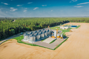 Grain elevator with metal containers for storing millet. Agricultural landscape in spring aerial view
