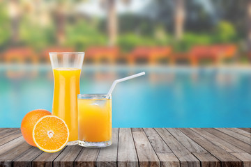 Summer Vacation Concept : Welcome drink orange juice punch put on wooden table nearly swimming pool with blue water and daybed in background.