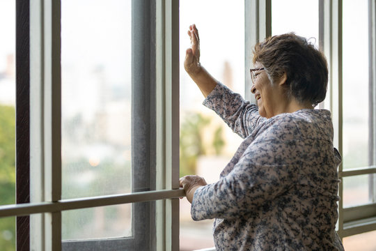 Anciana en aislamiento saludando frente a ventana. Lima, Peru