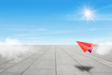 Freedom Concept : Red paper plane flying over concrete floor to blue sky.