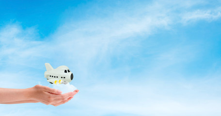 Travel Insurance Concept : Hand holding and take care white airplane model toy flying in blue sky.