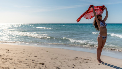 Portrait of young woman in bikini on tropical beach looking away from the camera. Beautiful girl in swimwear. Summer vacation and tanning concept.