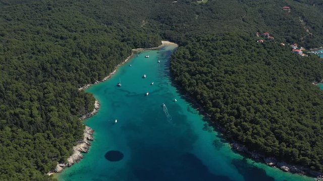 Beautiful Turquoise Cove with mediterranean sand beach, anchored Sailboats and tourists swimming, Island of Rab in Croatia - Aerial View