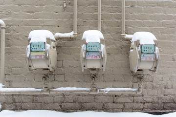 Three electric power meters on a wall in the snow