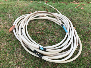 Old white water hose, The white rubber hose for watering the garden is placed on the lawn