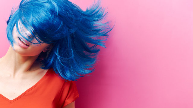 studio portrait of a sexy beautiful girl with a smile in motion on a pink background. Girl with blue hair