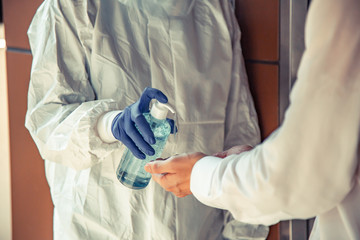 Officer Squeezing gel to people hands for wash hand by sanitizer gel dispenser, against Novel coronavirus or Corona Virus Disease (Covid-19) at front office. Antiseptic, Hygiene and Healthcare concept