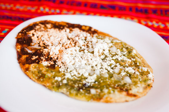 Mexican sopes with grated cheese and green salsa, mexican food spicy in mexico