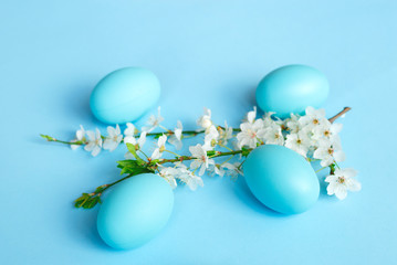 White spring branch of flowers with easter eggs on a blue background