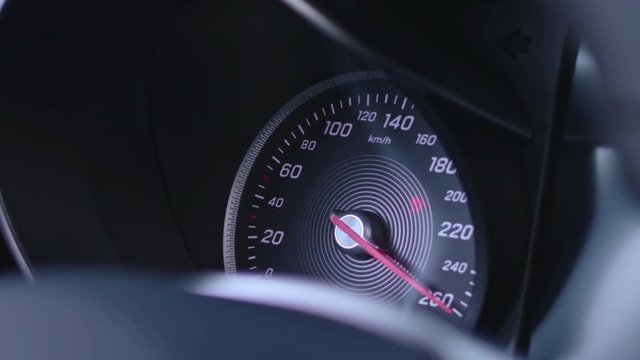 Detail shot of a speedometer in a car with black interieur going from zero to full speed when the car is turned on.