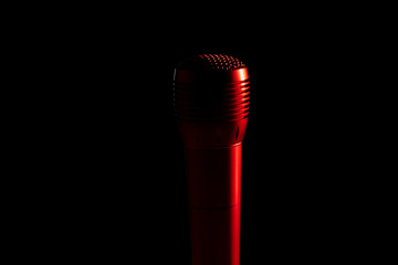audio microphone on a stand in a black dark background, red backlight