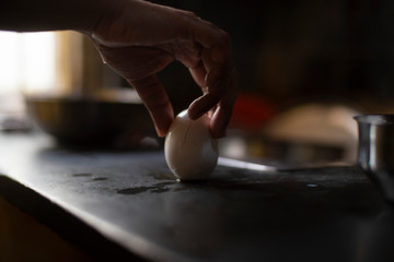 Woman displaying and trying to peel off the shell of the boiled egg in an Indian kitchen. Indian lifestyle in lock down.