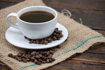 A cup of black coffee and coffee beans.