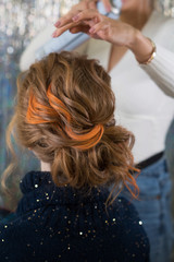 Fototapeta premium Hairdressing services. Creation of evening hairstyles fashionable stylish women's hairstyles. Hair styling process. Hairtician fixes hair with hair spray. Back view. Elegant colored hairstyle. Trendy