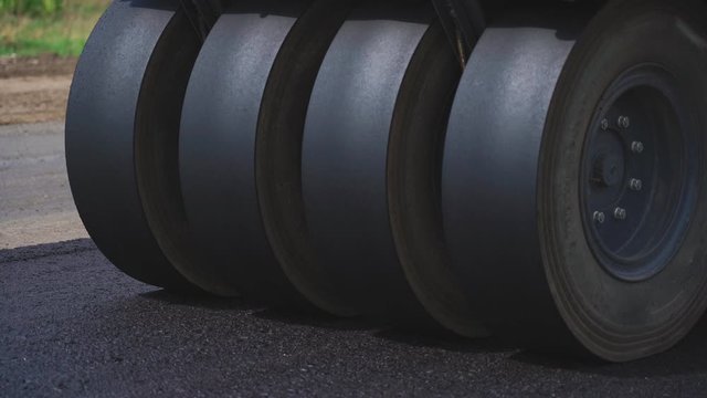 Roller machines make new asphalt roads. The asphalt paver squeezes hot asphalt.