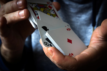 A deck of playing cards in hand, shuffling the deck, gambling.